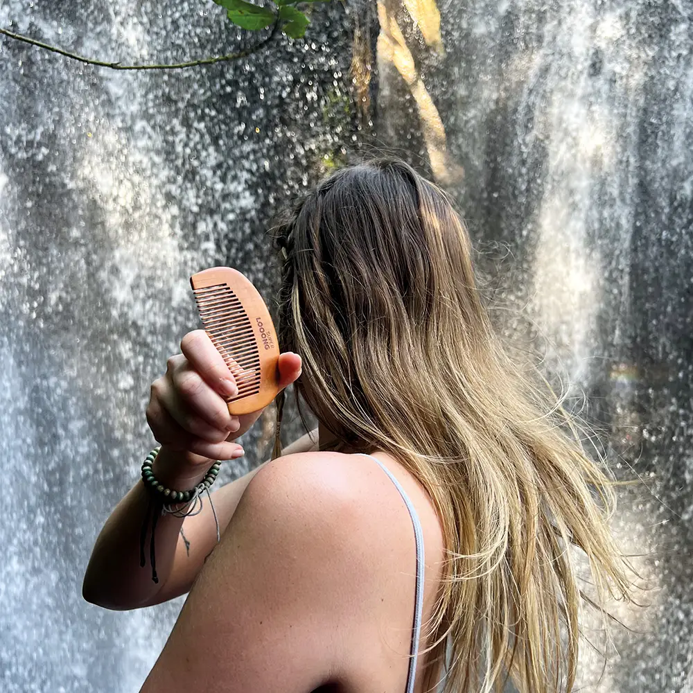 packshot modèle féminin tenant le peigne anti-static de superlooong avec comme fond une casacade d'eau à bali